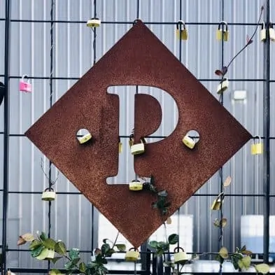 Trellis with locks locked to it and a rusty diamond with P cut out attached