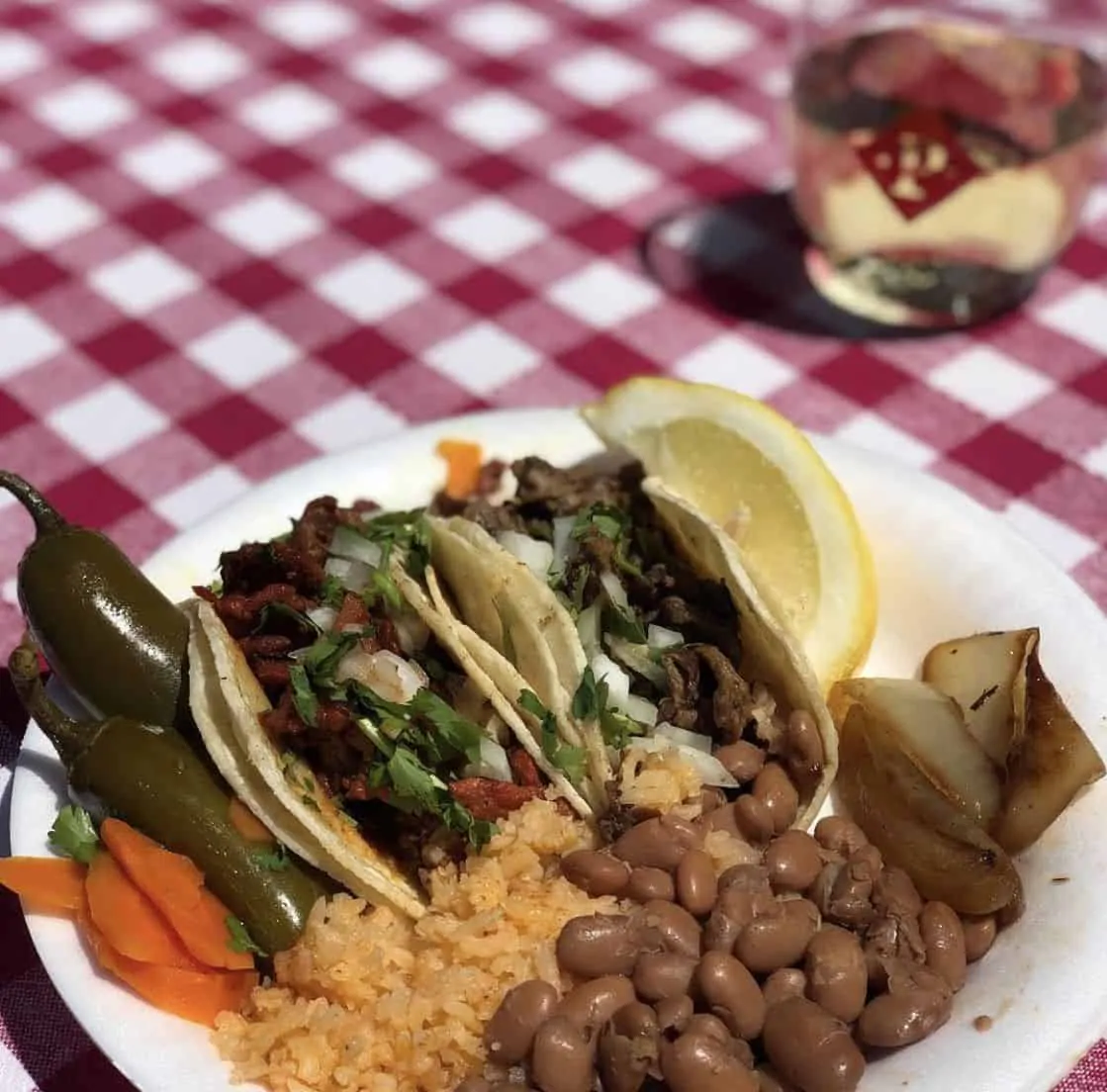 taco plate with rice, beans, tacos and a glass of wine