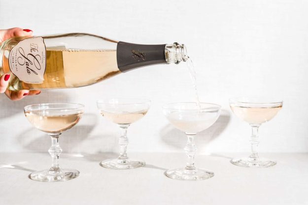 Bottle of Gala Sparkling wine pouring into coupes