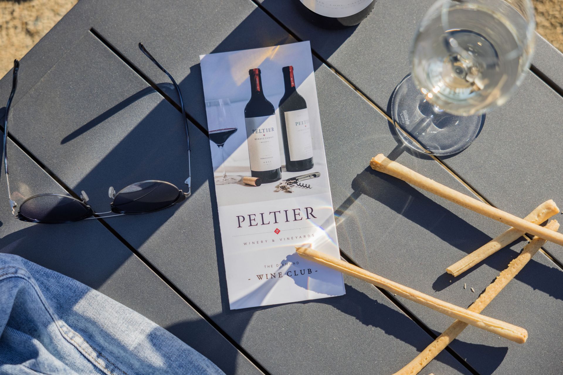 wine club brochure on table with wine breadsticks and sunglasses
