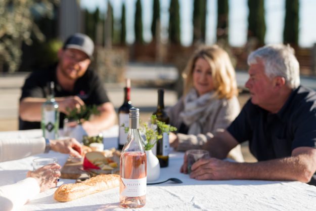 bottle of rosé on white tablecloth with people in background drinking wine
