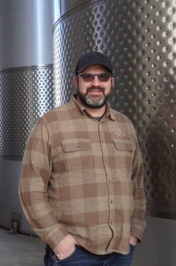Head Winemaker,Gianni Abate in brown plaid flannel and grey hat in front of stainless steel wine tanks