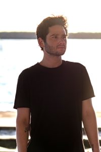 Darien Fields in black Tshirt standing in front of body of water