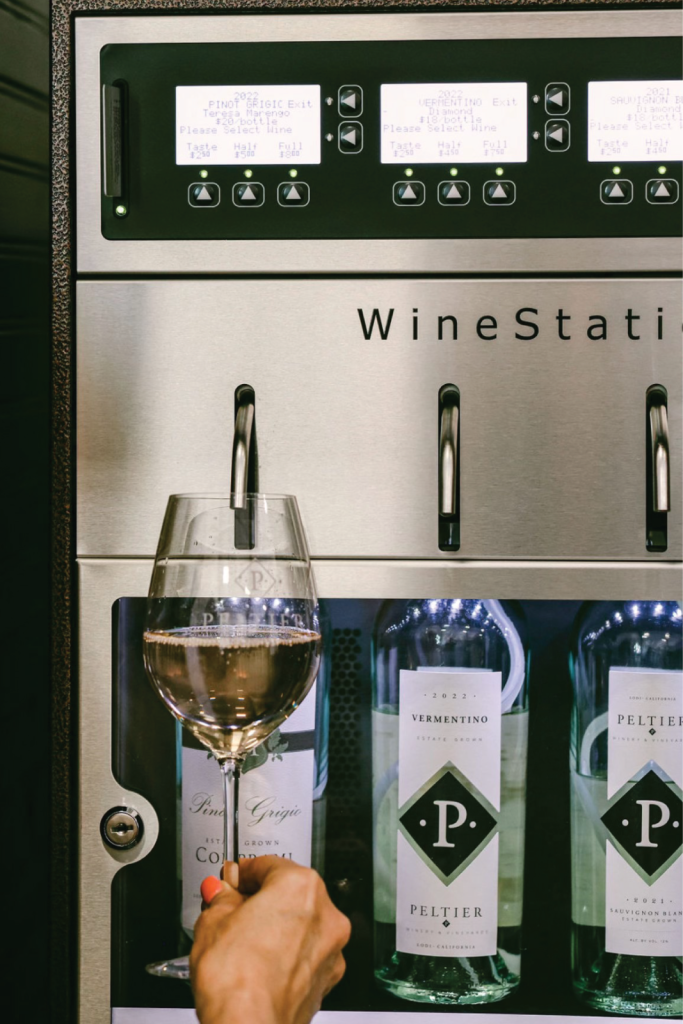 hand holding wine glass up to spout to dispense wine
