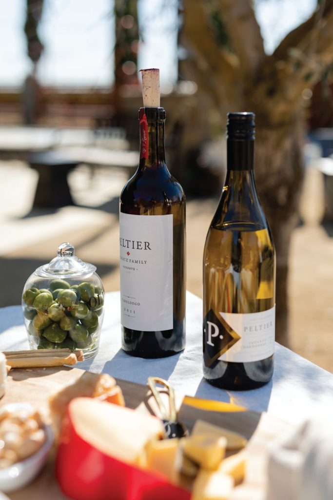 bottles of wine on table with cheese and olives