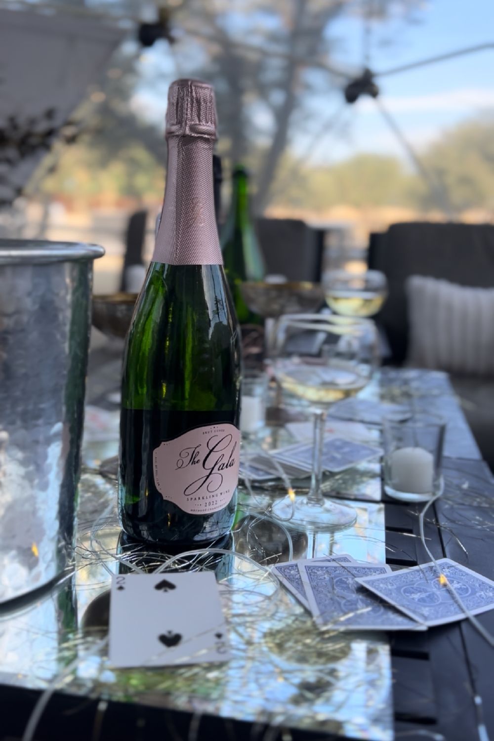 The Gala Sparkling Suite: a bottle of The Gala brut on a table with glasses, playing cards and an ice bucket The Gala Sparkling Suite: a bottle of The Gala brut on a table with glasses, playing cards and an ice bucket