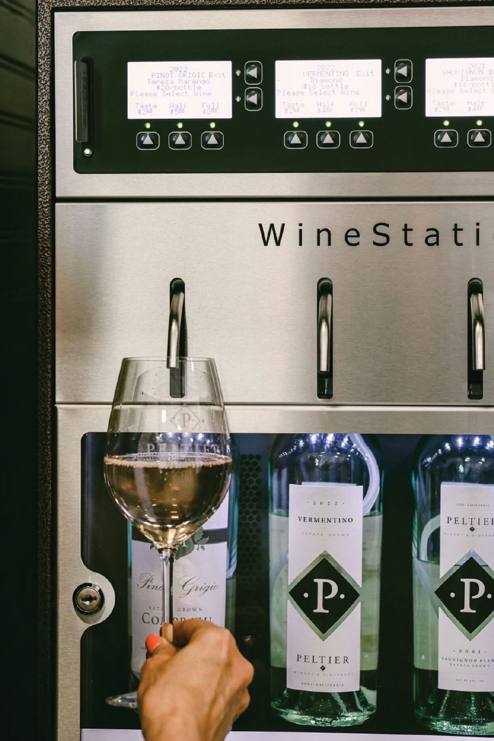 hand holding up wineglass to wine station hand holding up wineglass to wine station