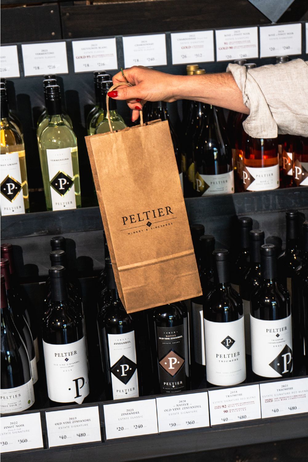 guest holding Peltier bag in front of metal rack with bottles guest holding Peltier bag in front of metal rack with bottles